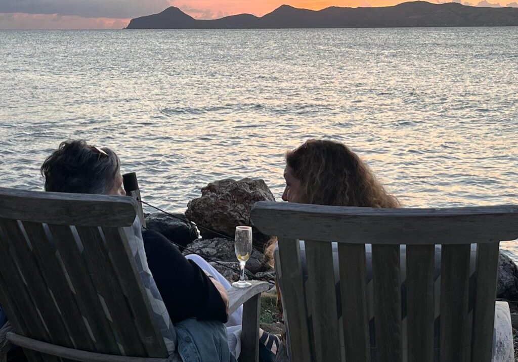 Two people enjoying a sunset view by the water with drinks.