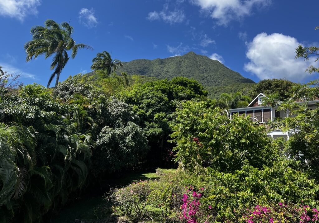 Lush green landscape with a mountain under a partly cloudy sky.