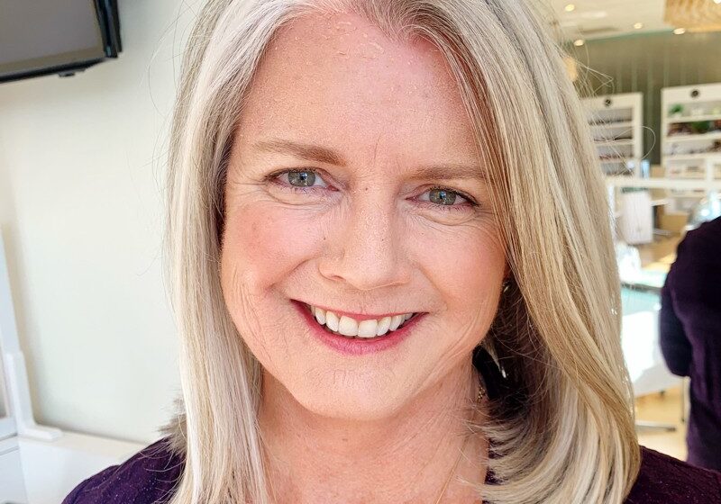 Smiling woman with blonde hair in a purple top.