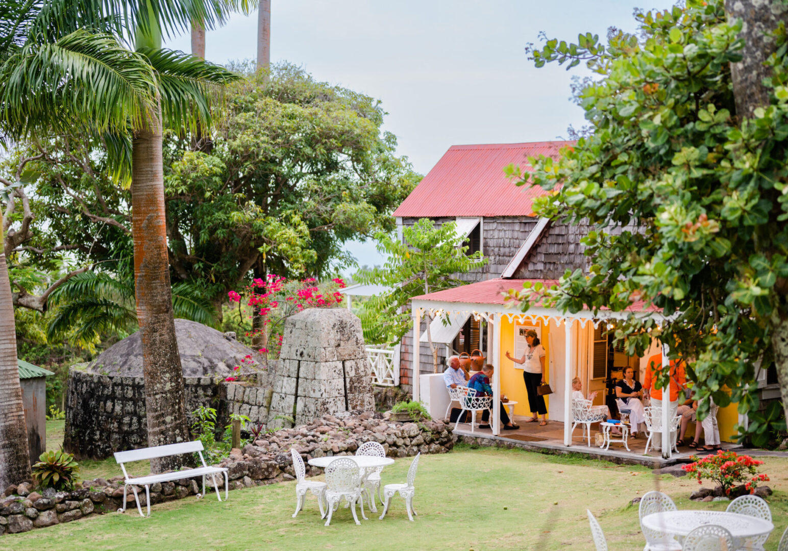 Cozy outdoor cafe seating surrounded by lush greenery and charming buildings.